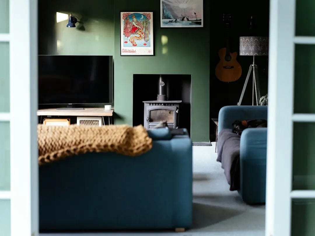 Un salon aux murs verts avec un téléviseur éteint sur un meuble bas, une Smart TV prête pour Premier IPTV